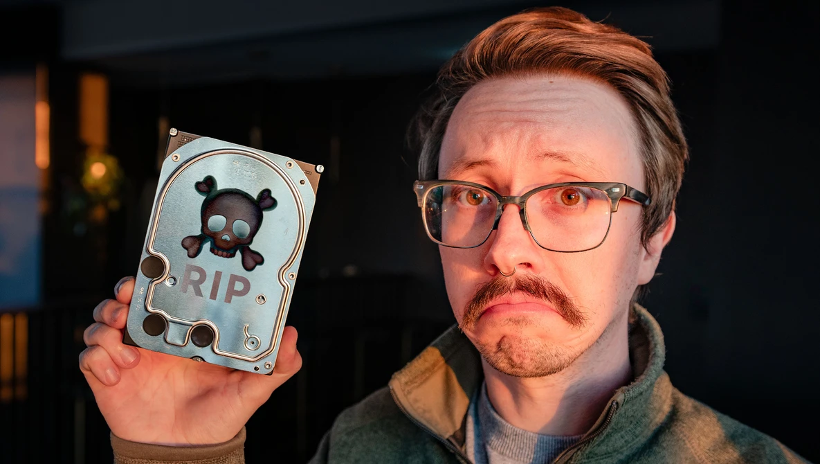 Person holding a decorative hard drive with skull and crossbones design labeled RIP.