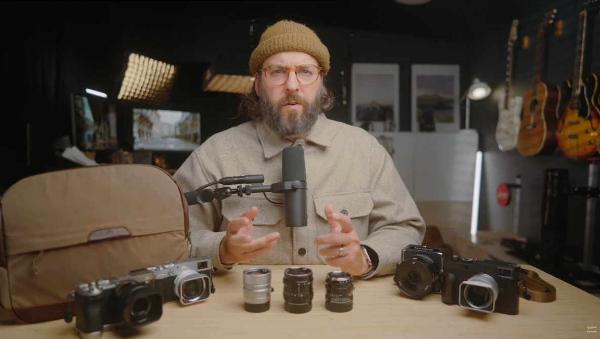 Photographer demonstrating vintage camera lenses arranged on a table during a studio discussion.