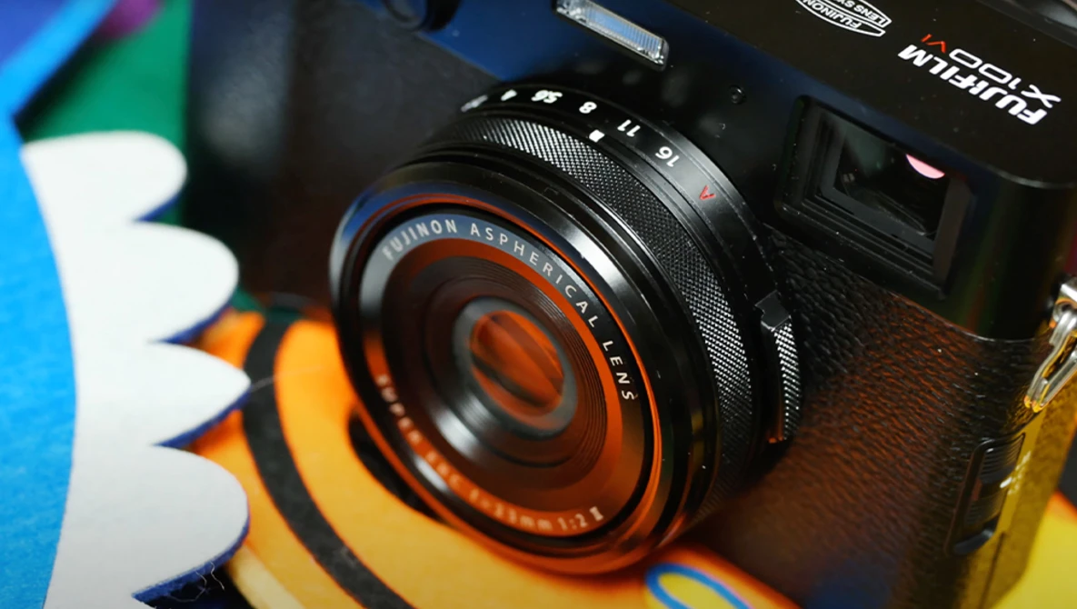 Vintage Minolta camera lens with orange and black detailing mounted on camera body.