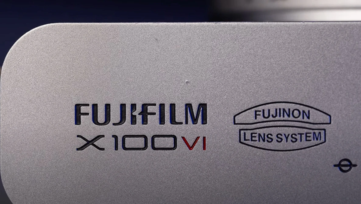 Close-up of Fujifilm X100VI camera body showing branding and Fujinon lens system marking.