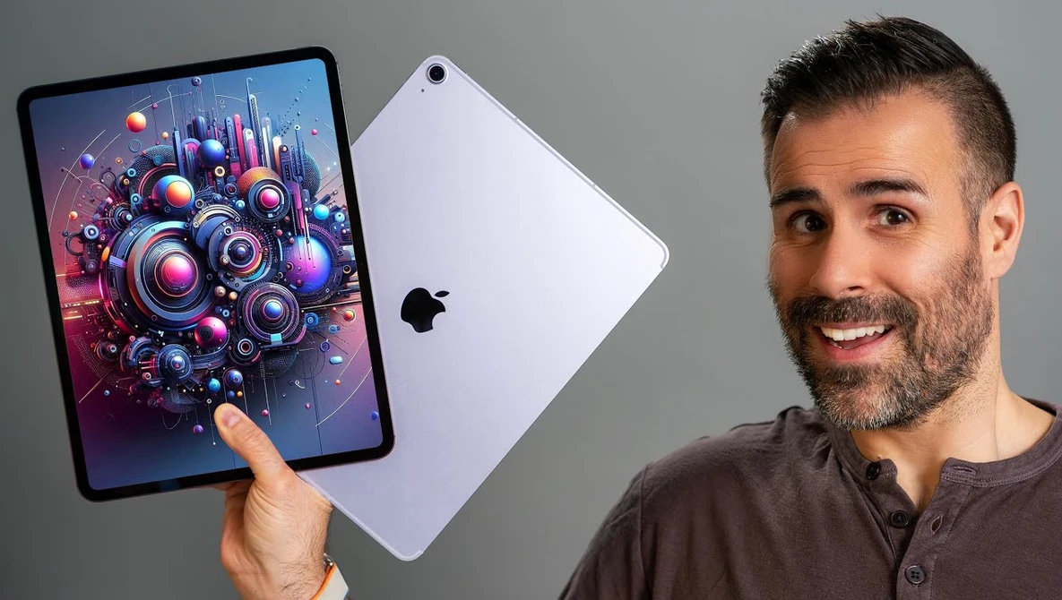 Man holding iPad displaying vibrant digital artwork of colorful mechanical gears and spheres.