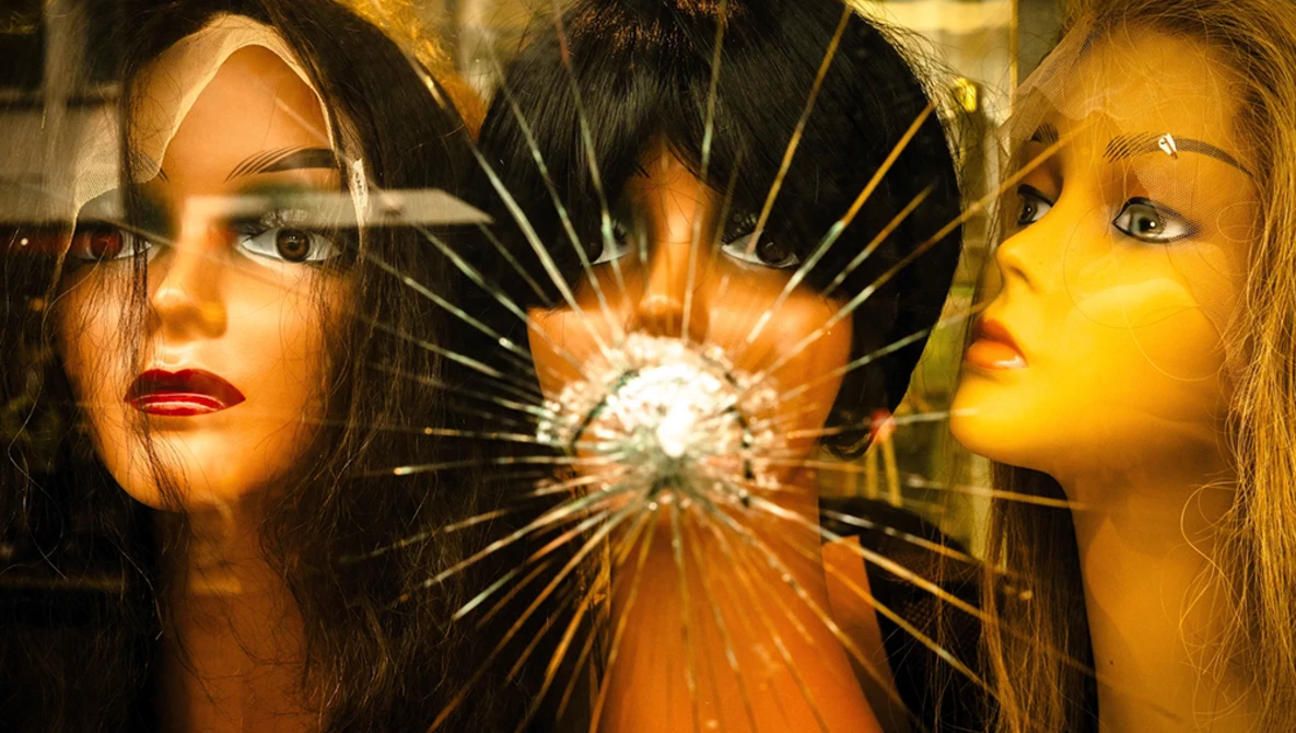 Two women's faces flanking a shattered glass center with radiating light rays.