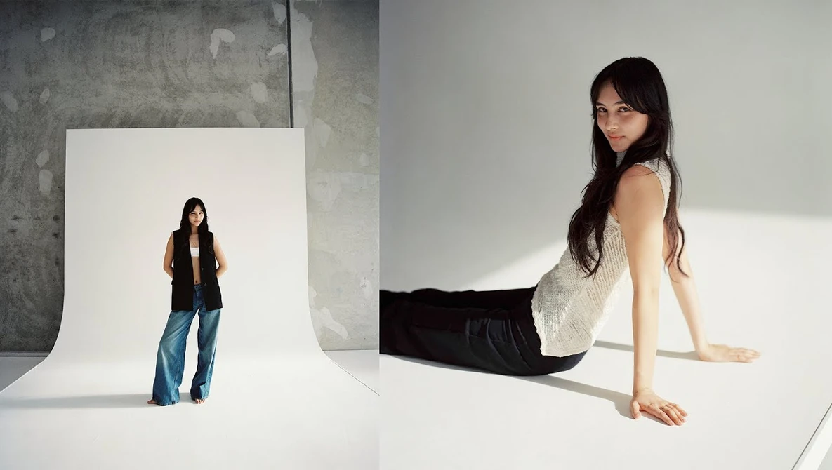 Woman posing on white seamless backdrop with studio lighting, shown both in foreground and as reflection in background setup.