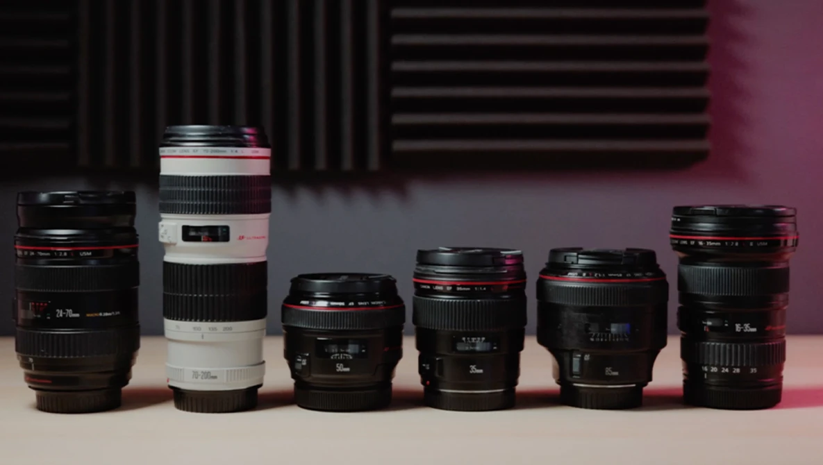 Six camera lenses arranged in a line, displaying varying focal lengths and designs against a pink and dark background.