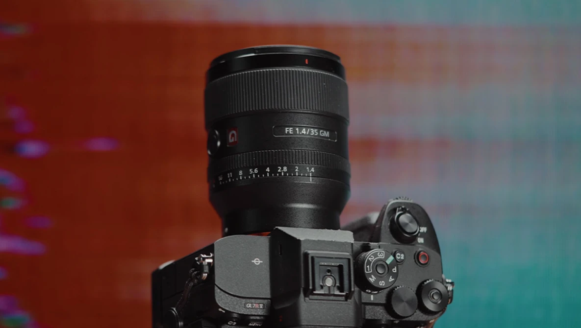 Sony mirrorless camera with FE 1.4/35 GM lens mounted against warm and cool gradient backdrop.