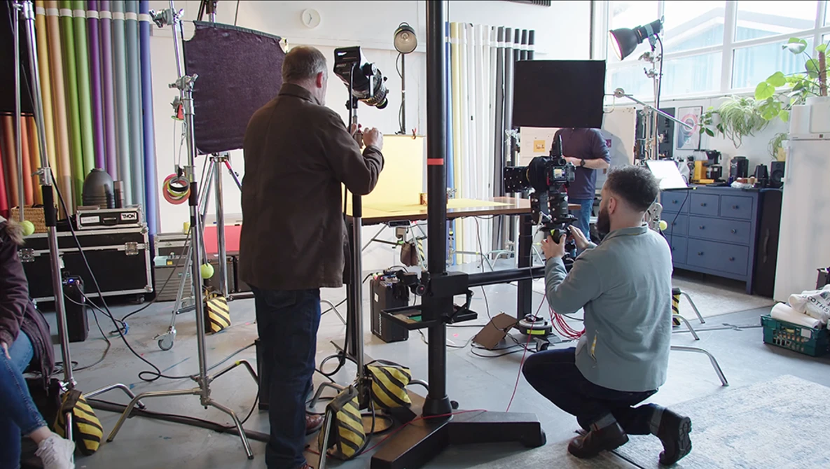 Professional photography studio setup with crew operating camera equipment and lighting rigs during a production shoot.