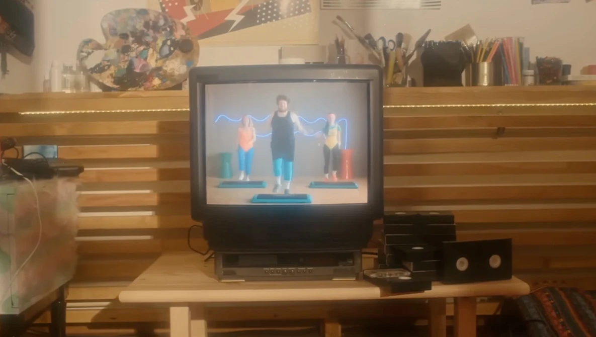 CRT television displaying three people standing on a blue platform against a blue background.