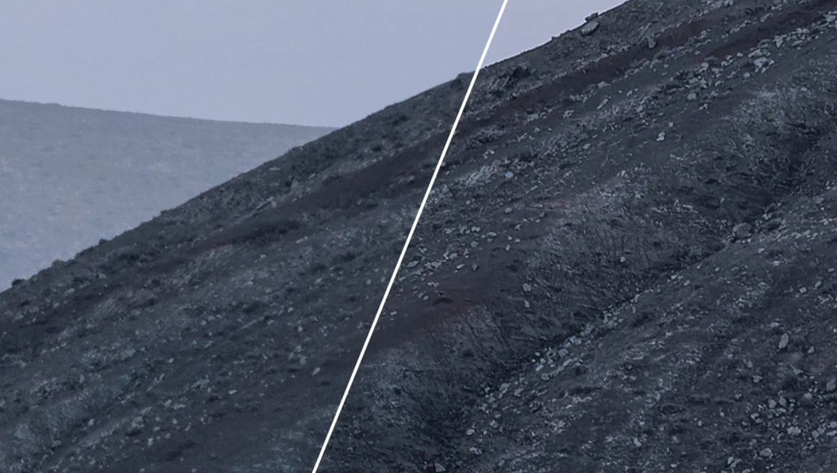A white rope or cable cutting diagonally across dark, rocky slopes under overcast sky.