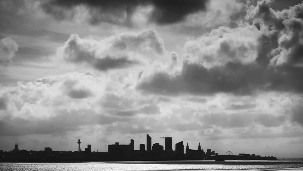 Silhouetted city skyline against dramatic cloudy sky and calm water.