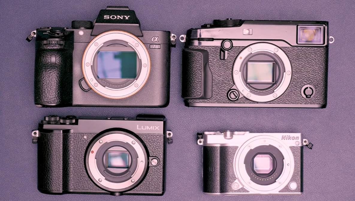Four compact digital cameras arranged on a purple background, displaying various form factors and designs.