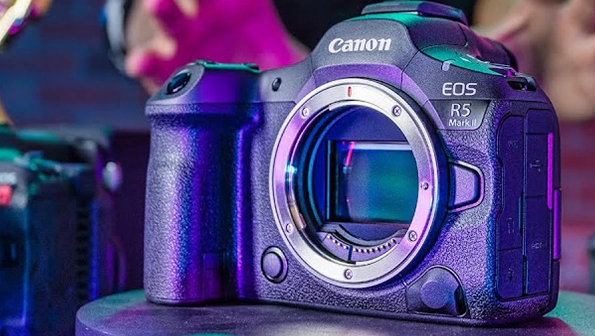 Canon EOS R5 mirrorless camera body displayed against colorful purple and cyan lighting.