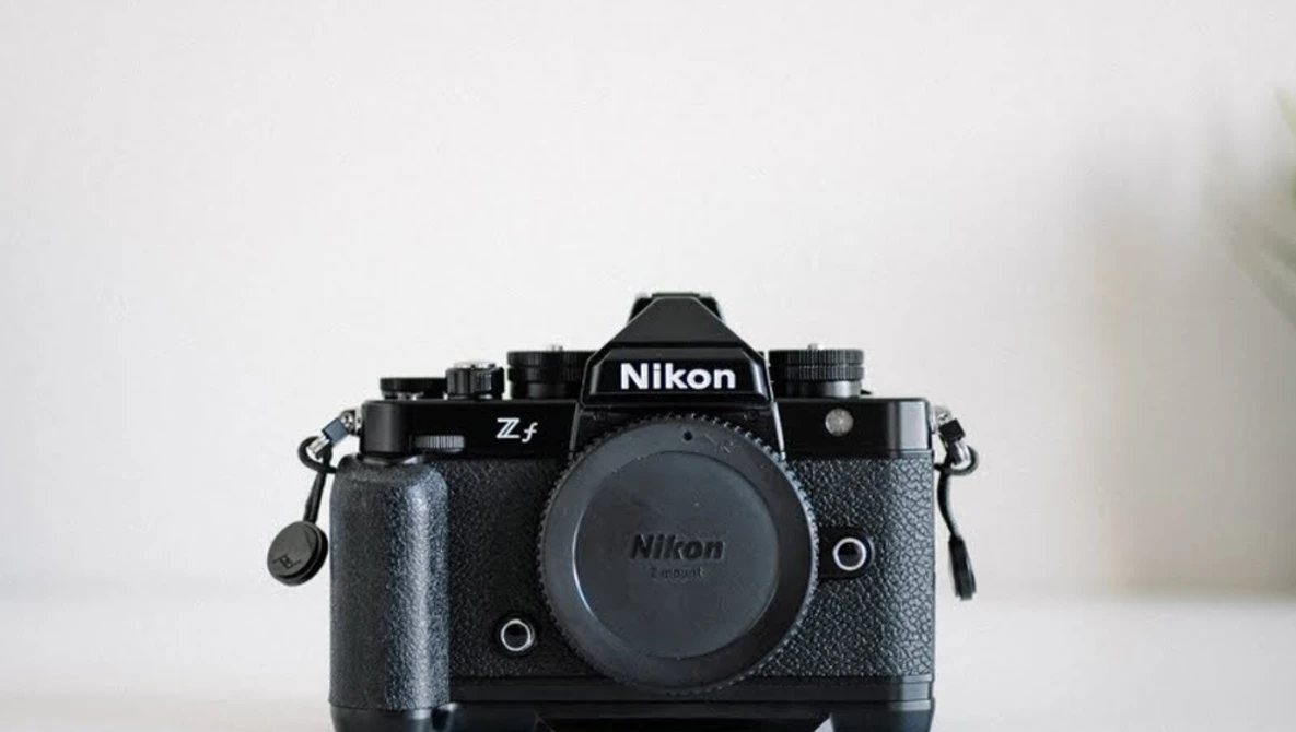 Nikon Z f mirrorless camera body with attached battery grip against white background.
