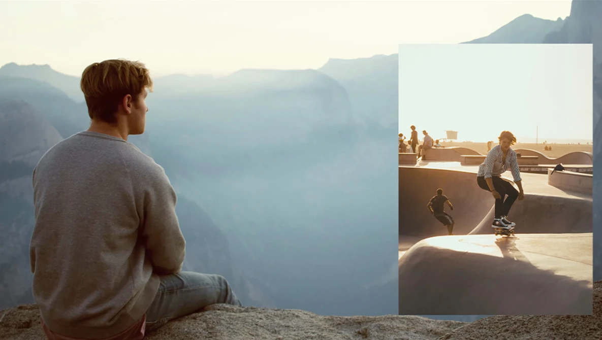 Man sitting on a cliff edge overlooking a misty mountain valley at sunrise or sunset.