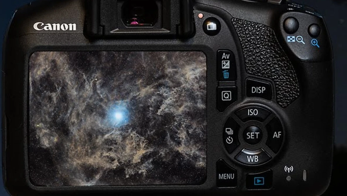 Canon DSLR camera displaying a deep space image with nebula and bright star on its rear LCD screen.