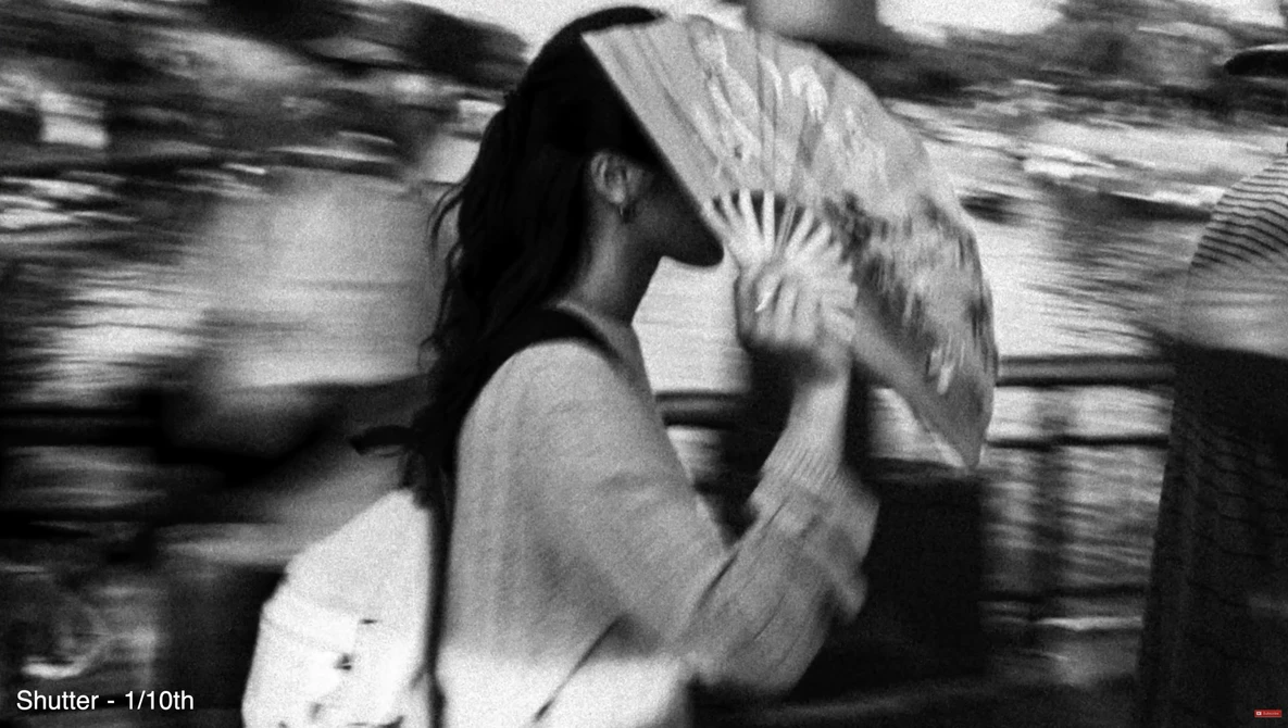 Person in motion holding a fan in front of their face, shot with motion blur and fast shutter speed.