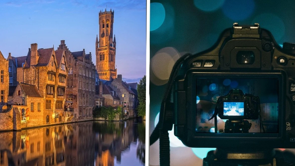 Medieval European canal city at dusk reflected in still water, with a tall bell tower illuminated against twilight sky.
