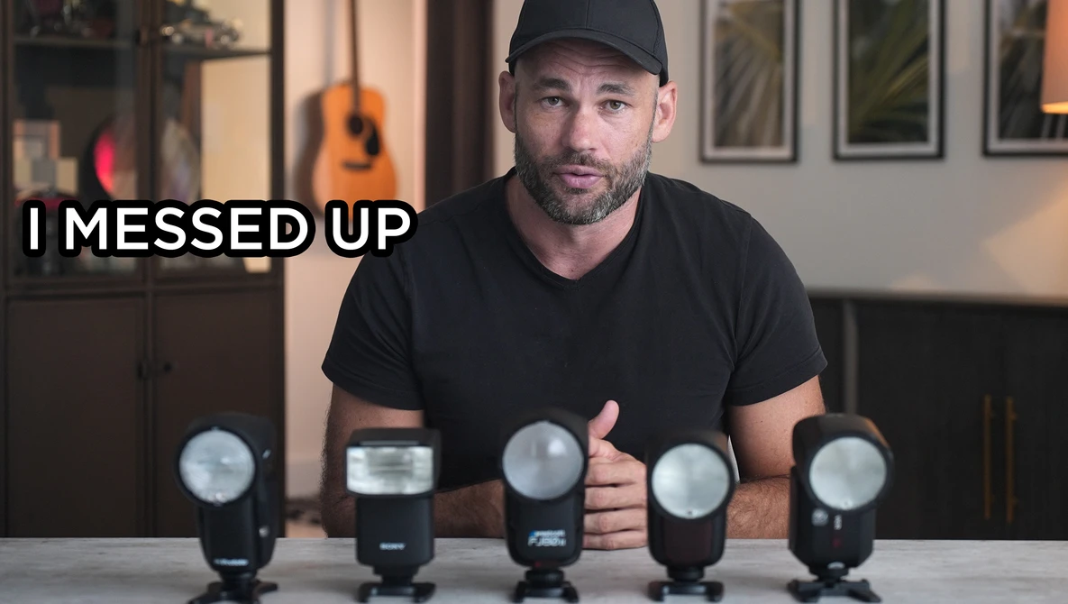 Photographer with five camera flash units arranged in a row on a table, appearing to address a mistake.