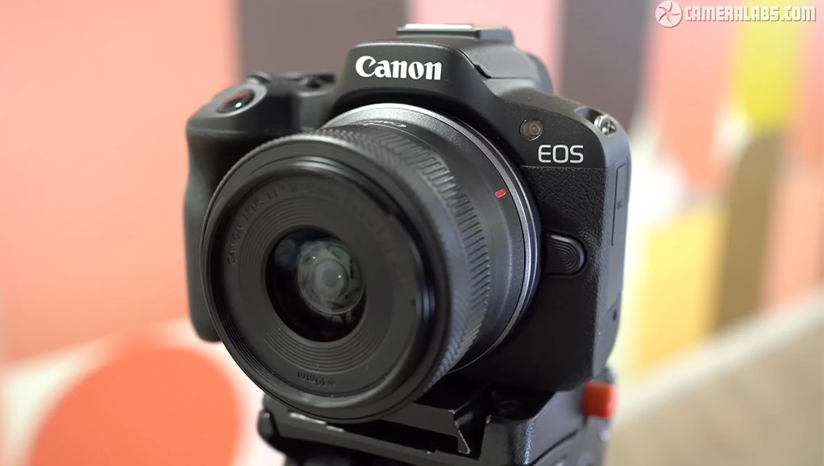 Canon EOS R50 mirrorless camera with RF-mount lens mounted, displayed against a colorful blurred background.
