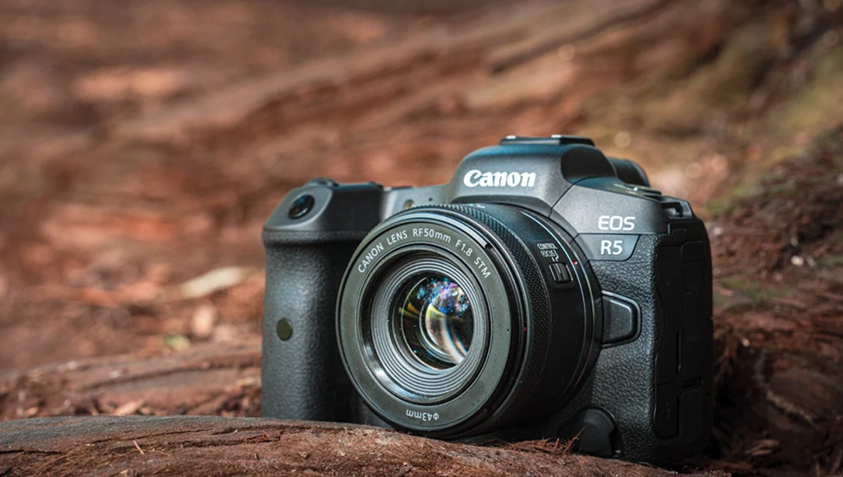 Canon EOS R5 mirrorless camera with RF mount lens on weathered wood surface.