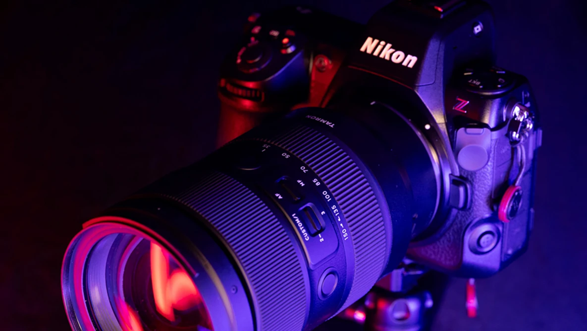 Nikon Z camera with attached lens, illuminated by red and blue studio lighting against a dark background.