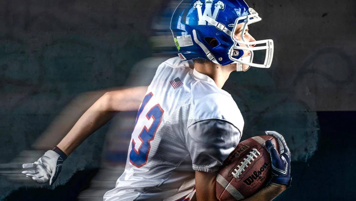 Football player in blue and white uniform holding ball with motion blur effect.
