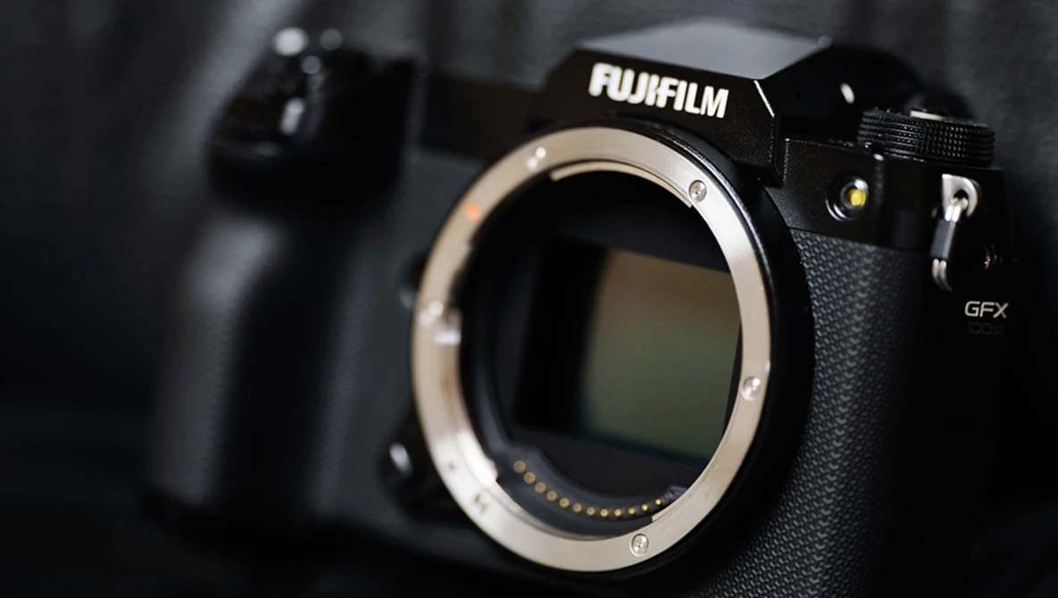 Fujifilm GFX camera body with lens mount exposed, shot against dark background with shallow depth of field.
