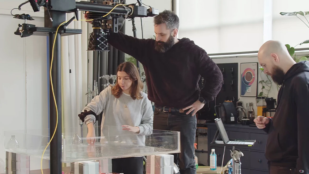 Three people gathered around a light table examining photographic prints in a studio setting.