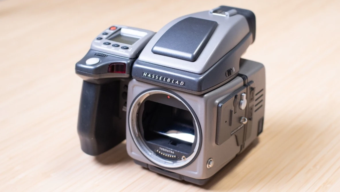 Hasselblad 500 series camera body with digital back and control unit mounted on wooden surface.