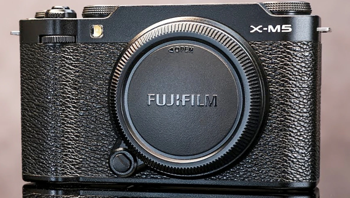 Fujifilm X-M5 mirrorless camera body with black textured grip and dark lens cap.