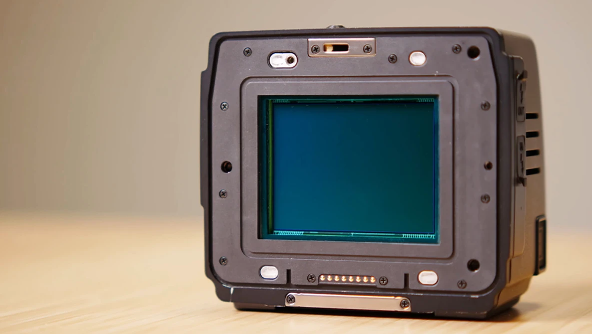 Rugged portable device with a teal-colored CRT display and metal frame, photographed against a neutral beige background.