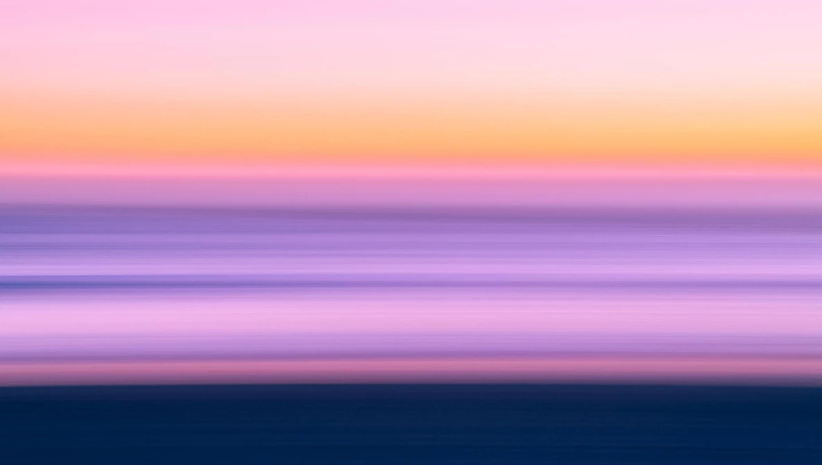 Serene seascape with layered horizontal bands of soft pink, purple, and blue tones during twilight hour.
