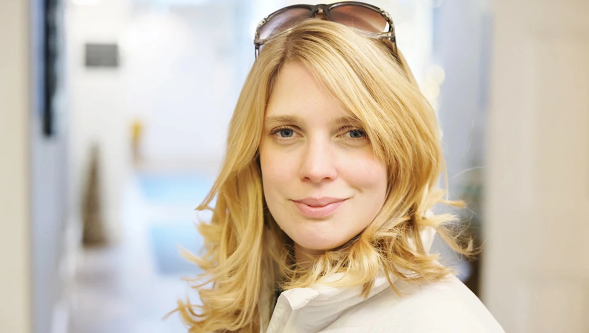 Woman with shoulder-length blonde hair wearing sunglasses on her head, looking at camera with neutral expression.