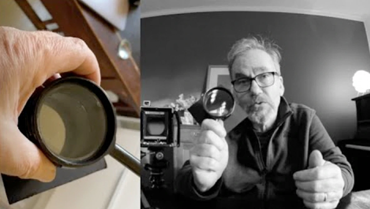 Photographer holding a circular lens filter next to a vintage film camera and light meter during a studio setup.