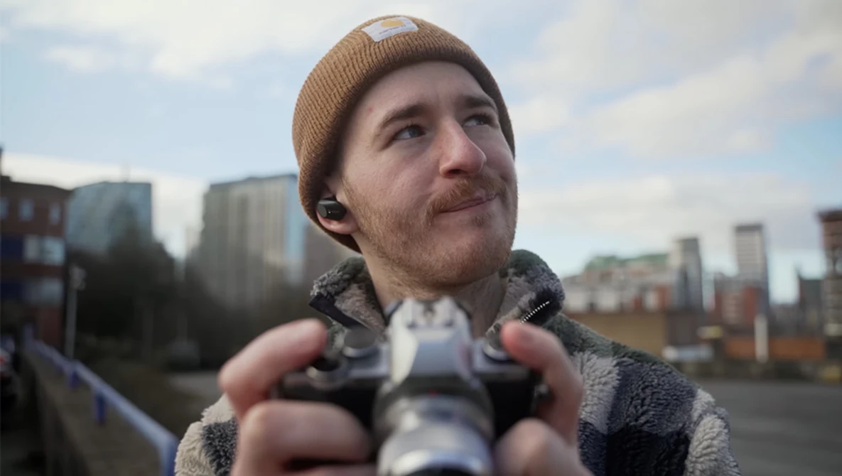 Man holding binoculars while looking upward against urban skyline backdrop.
