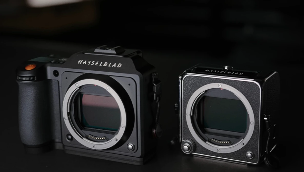 Two Hasselblad medium format cameras positioned side by side against a dark background.
