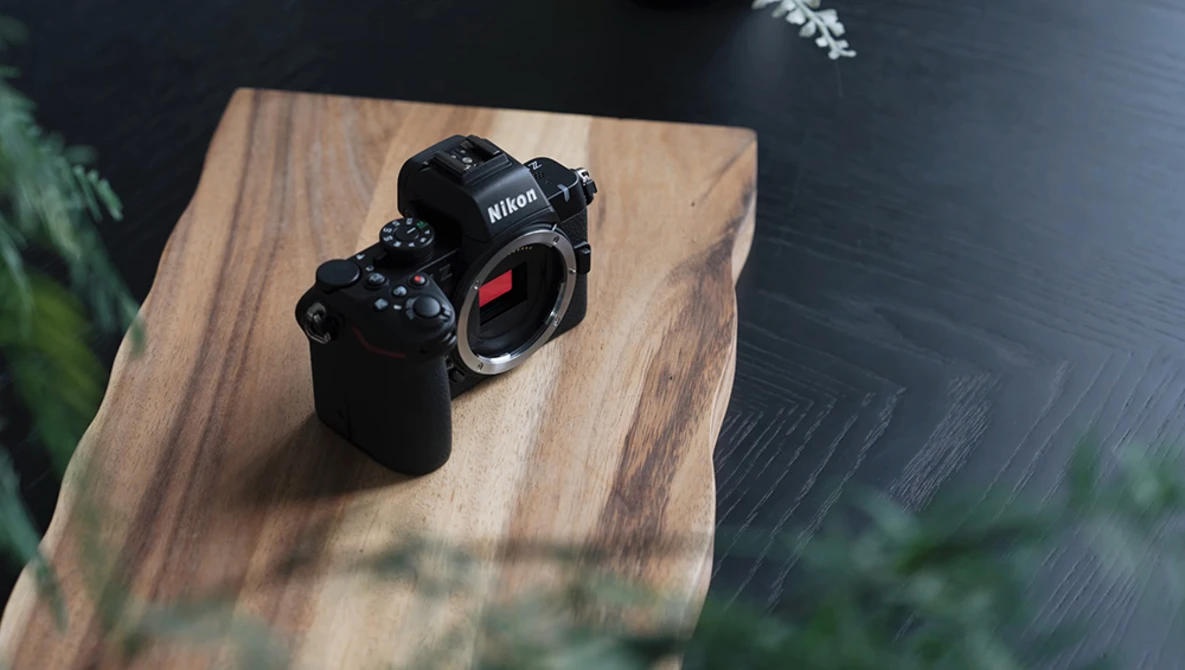 Nikon Z-series mirrorless camera body displayed on a wooden platform with natural window lighting.