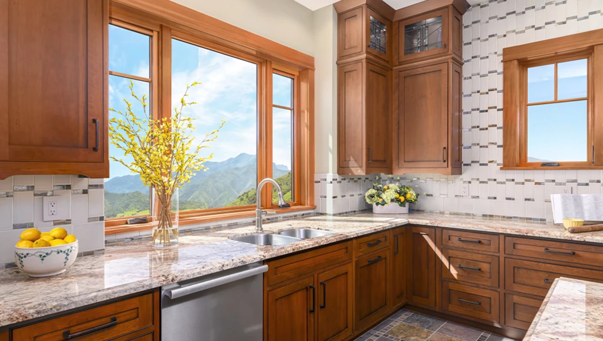 Luxury kitchen with wood cabinetry, granite countertops, and expansive windows overlooking mountains.