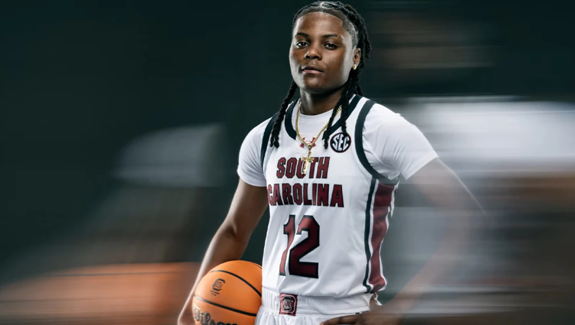 Basketball player wearing South Carolina white jersey number 12 holding a basketball.
