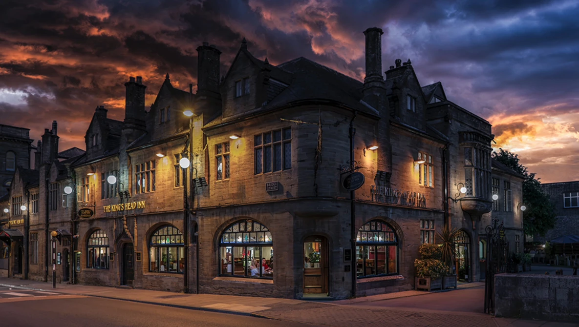 Historic brick building illuminated at dusk under dramatic orange and purple clouds.
