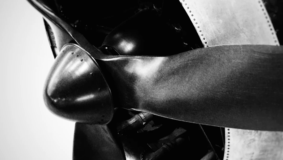 Close-up of aircraft propeller and engine cowling in black and white.
