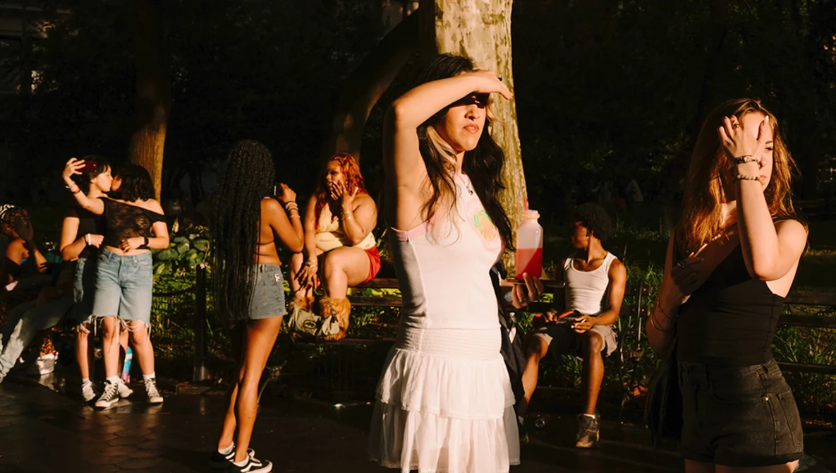 Woman in white dress dancing at outdoor evening celebration surrounded by guests.