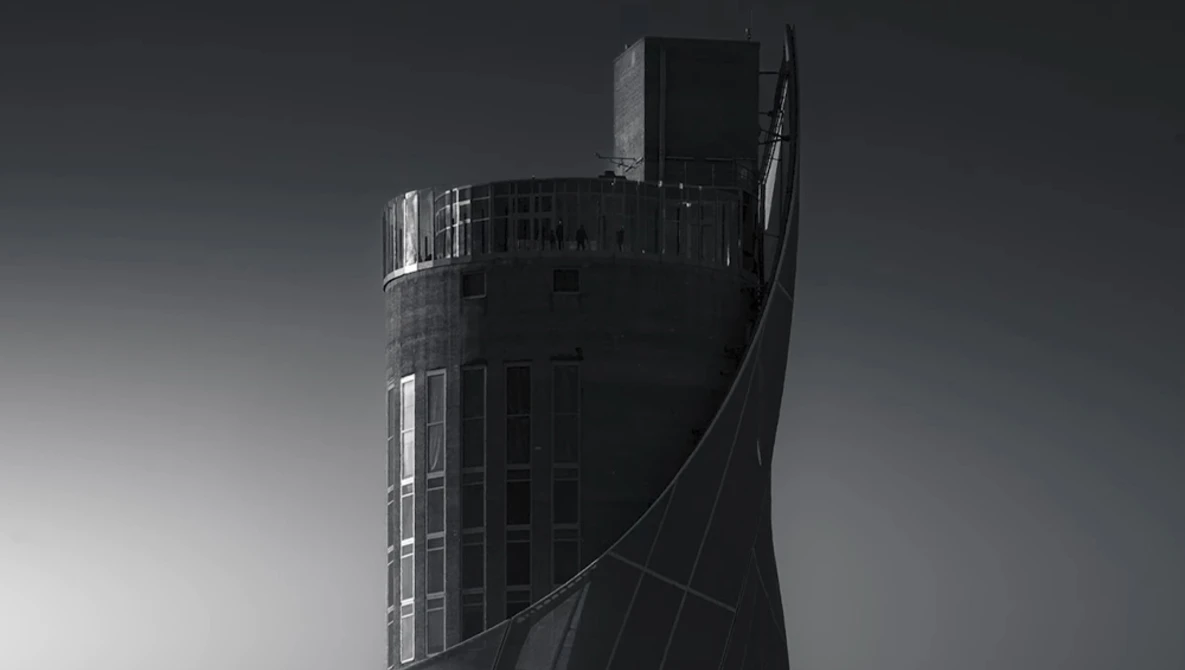 Modern cylindrical tower building with curved architectural elements photographed in monochrome.