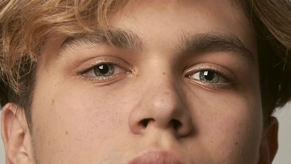 Close-up portrait of a young man with direct eye contact and neutral expression.