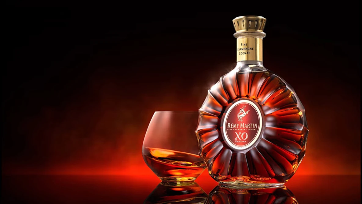 Cognac bottle and snifter glass against warm amber-lit background.