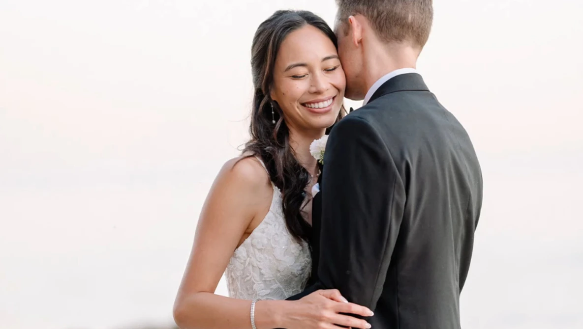 Bride and groom embracing during portrait session with soft studio lighting.