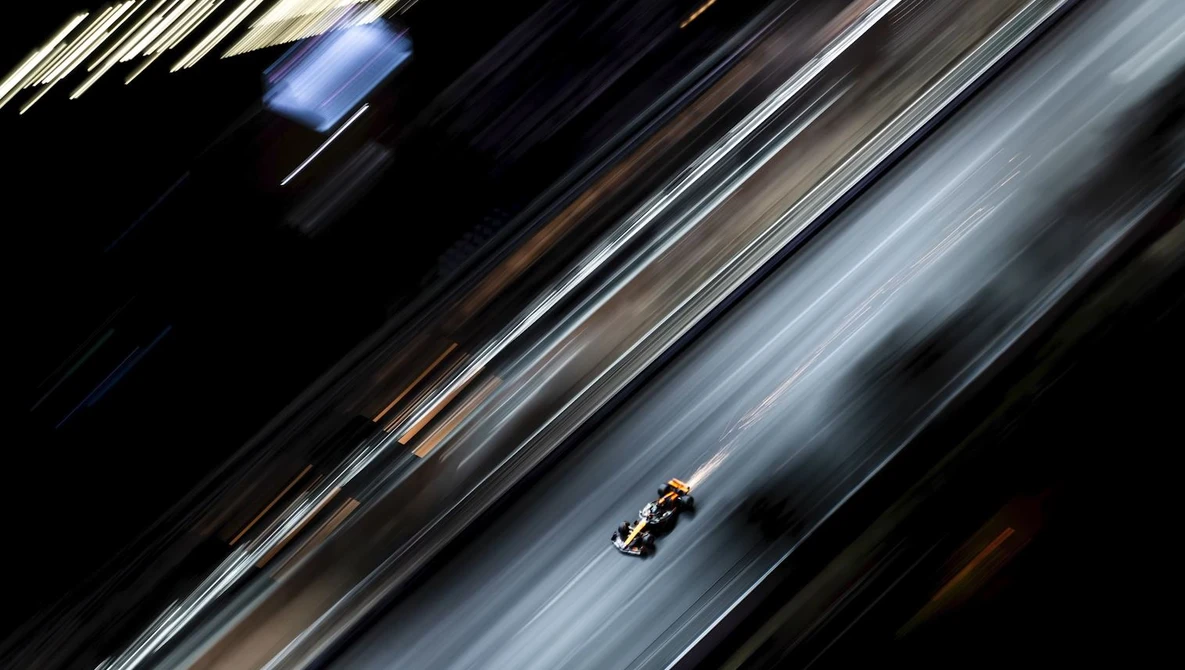 Formula One race car captured with motion blur on a diagonal asphalt track.