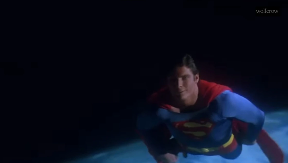 Person in superhero costume flying horizontally against dark background.