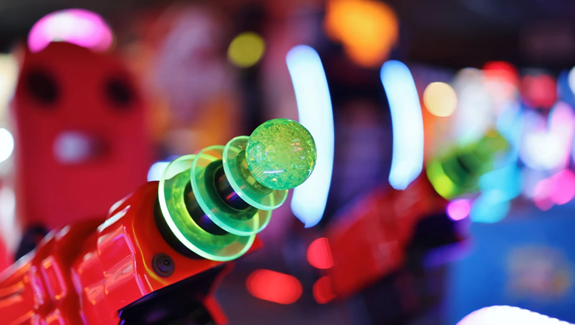 Close-up of a red party horn with green and black coiled paper, with colorful bokeh lights blurred in the background.