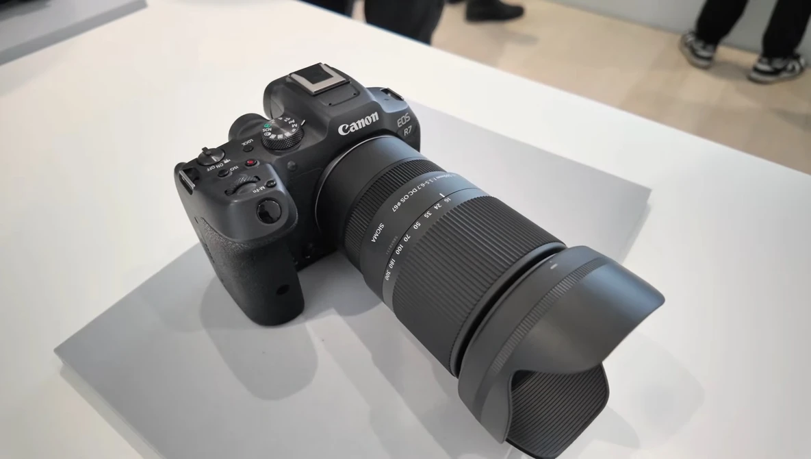 Canon mirrorless camera with telephoto lens mounted on white display surface.