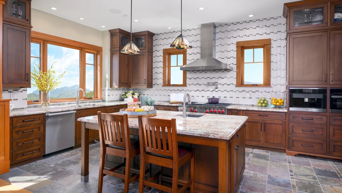 Bright kitchen interior with wood cabinetry, marble island, and geometric tile backsplash.